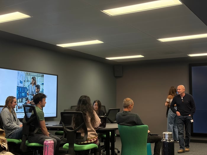 NICD AI trainees sat around a table, listening to Director, Barry, speak