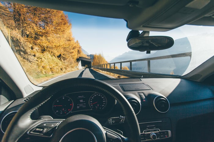 A car dashboard, with a mountain vista behind it.