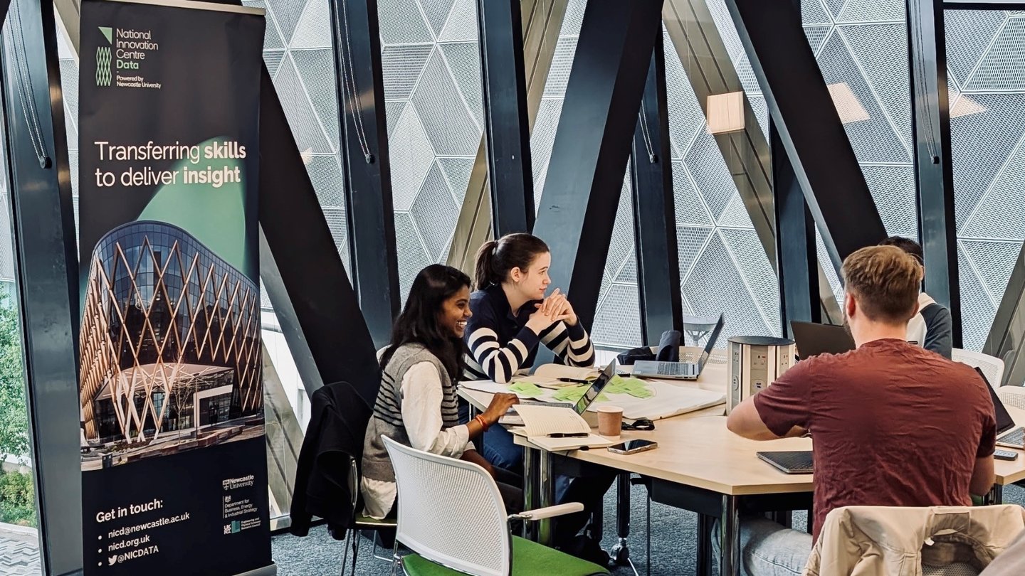 Three students sat around a table at a NICD bootcamp sessions