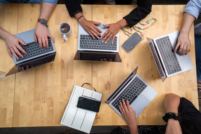 people working on laptops over a wooden table